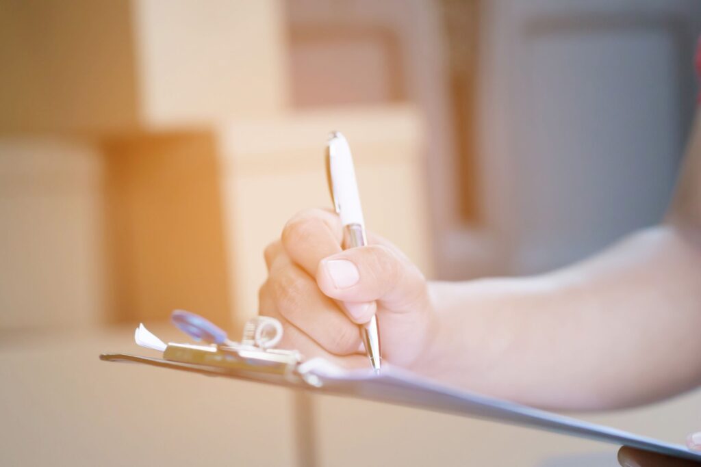 A mover's hand is writing something on the checklist.