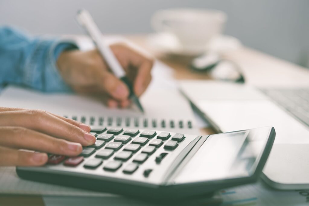 A man is using a calculator, notebook and pen in the concept of budgeting for house removals