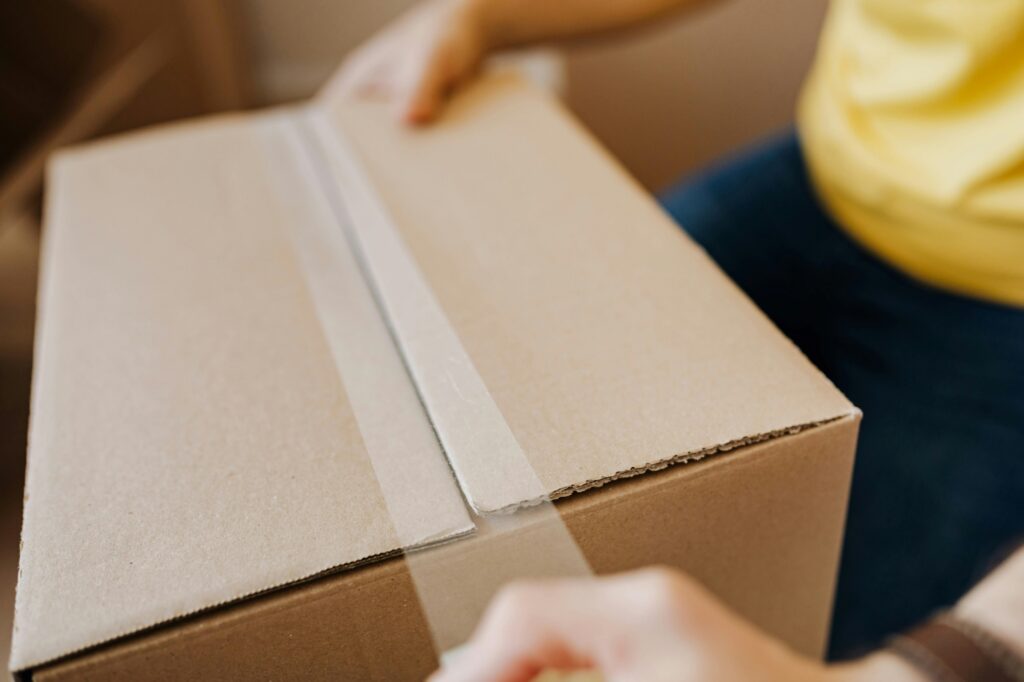 A cropped photo of a professional mover sealing a carton in the concept of Man and Van in Chelsea.